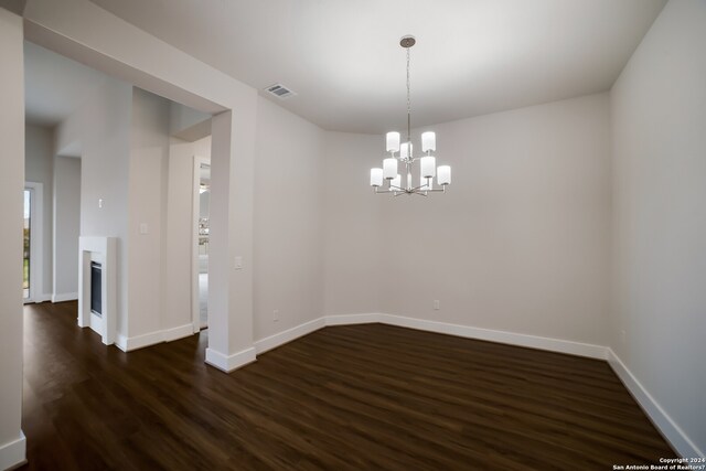 empty room featuring a notable chandelier and dark hardwood / wood-style flooring