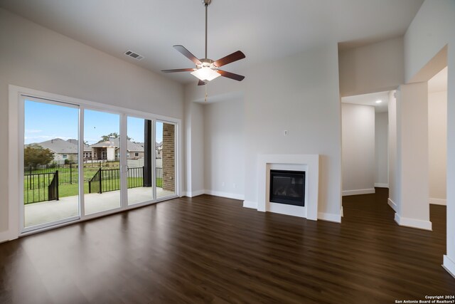 unfurnished living room with dark hardwood / wood-style flooring, ceiling fan, and a towering ceiling