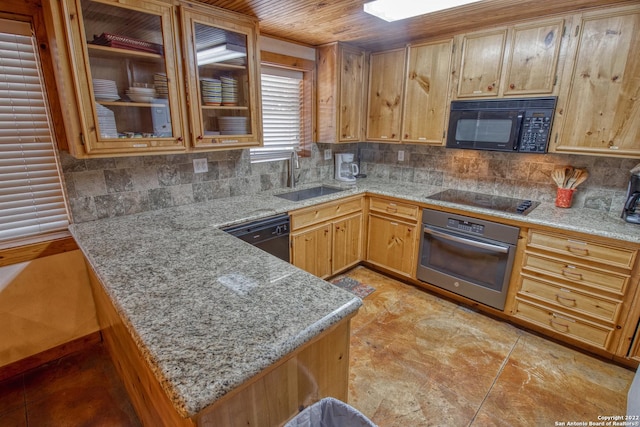 kitchen featuring light stone countertops, tasteful backsplash, black appliances, and sink