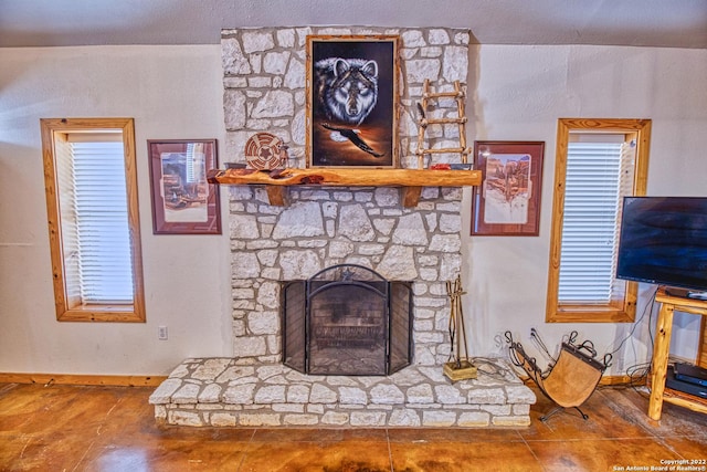 tiled living room with a stone fireplace