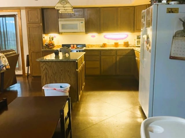 kitchen with white appliances, a center island, and light tile floors