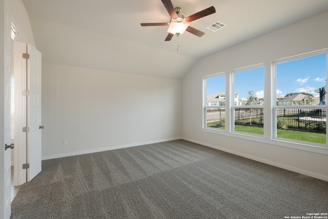 carpeted spare room featuring vaulted ceiling and ceiling fan