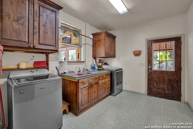 kitchen featuring light tile flooring, sink, and washing machine and dryer