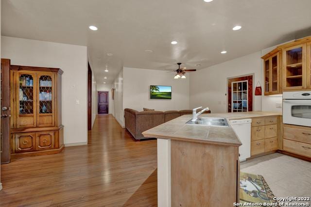 kitchen featuring white appliances, ceiling fan, sink, light hardwood / wood-style flooring, and tile countertops