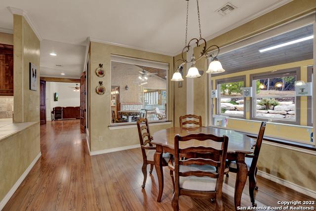 dining area with wood-type flooring and ceiling fan with notable chandelier