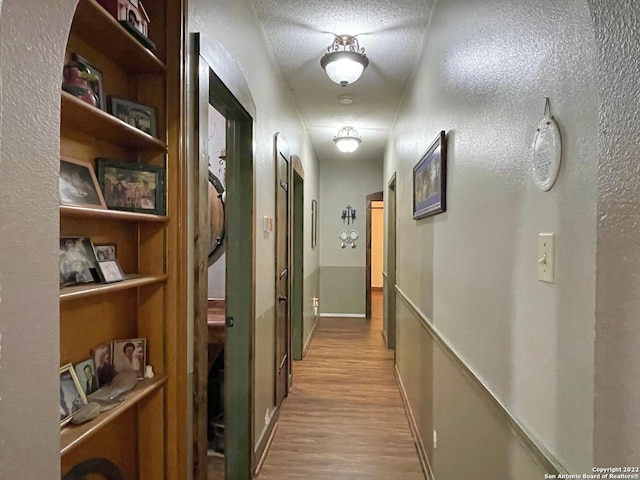 hallway with a textured ceiling and light wood-type flooring