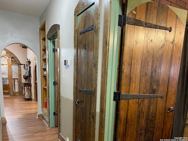 hallway with dark hardwood / wood-style flooring, wood walls, and a textured ceiling