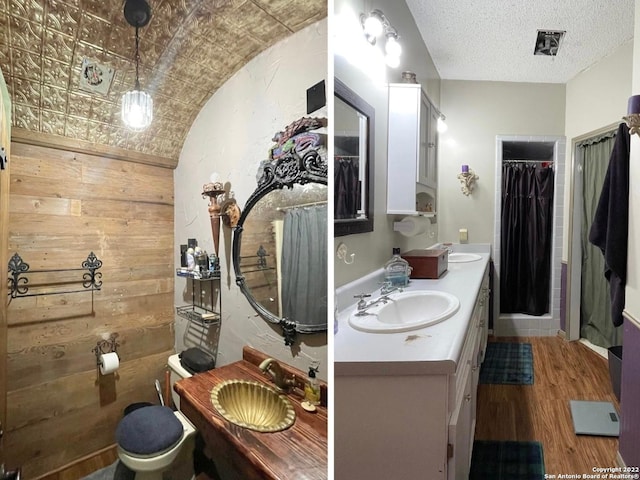 bathroom with wooden walls, double sink vanity, wood-type flooring, and toilet