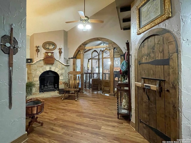 entrance foyer featuring vaulted ceiling, hardwood / wood-style floors, ceiling fan, and a fireplace