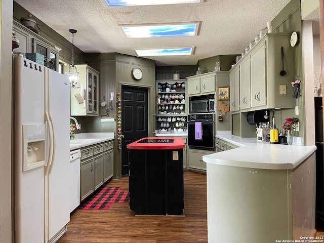 kitchen with a textured ceiling, hanging light fixtures, white appliances, and dark hardwood / wood-style floors