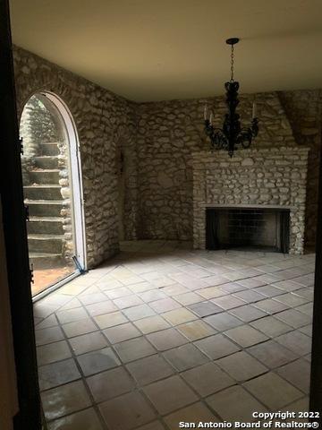 unfurnished living room featuring a fireplace, a chandelier, and light tile floors