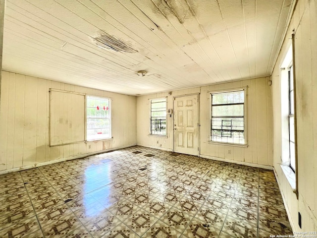 unfurnished room featuring light tile flooring and wood walls