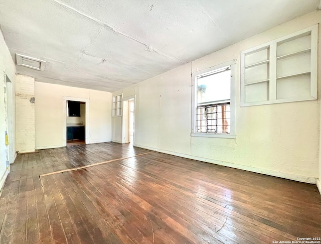 unfurnished room featuring built in features, dark wood-type flooring, and a textured ceiling