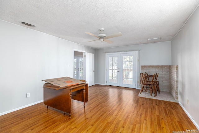 interior space with a textured ceiling, light hardwood / wood-style floors, ceiling fan, and french doors