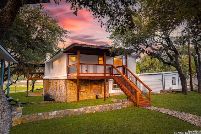 view of front of house featuring a deck, central AC unit, and a yard