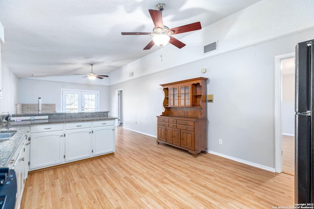 kitchen with black refrigerator, ceiling fan, a textured ceiling, light hardwood / wood-style flooring, and white cabinets