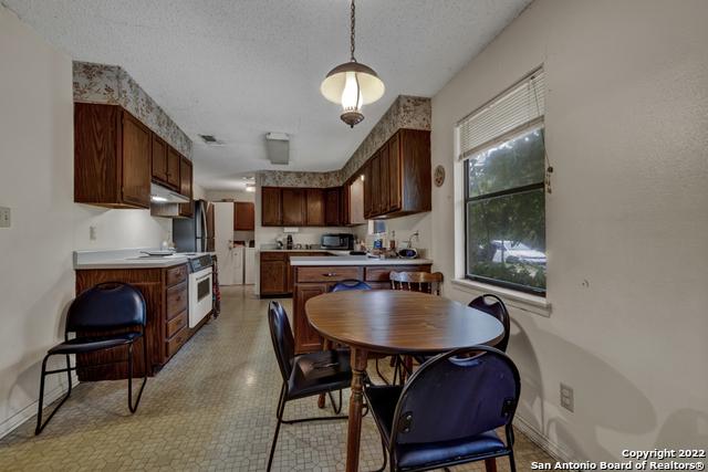 interior space featuring light tile floors, appliances with stainless steel finishes, hanging light fixtures, and a textured ceiling