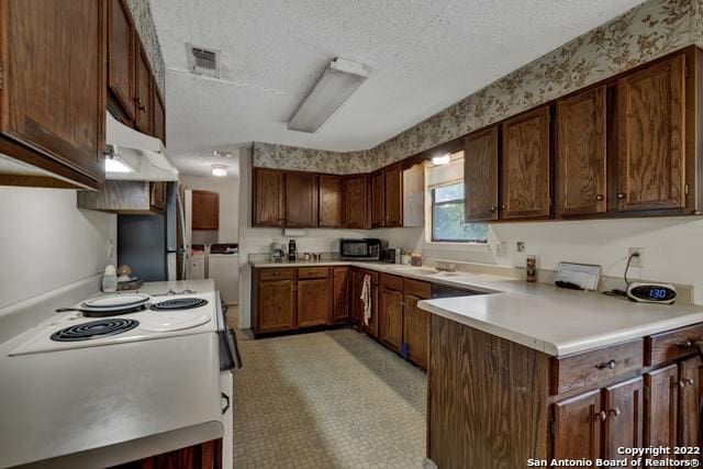 kitchen featuring light tile flooring, a textured ceiling, appliances with stainless steel finishes, dark brown cabinetry, and sink