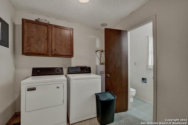 clothes washing area featuring light tile flooring, cabinets, washing machine and dryer, and a textured ceiling