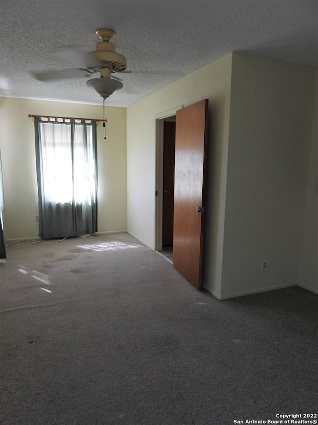 spare room featuring dark carpet, ceiling fan, and a textured ceiling