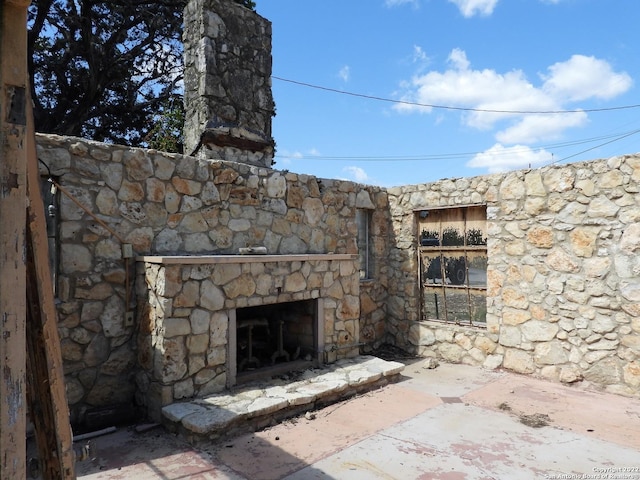 view of terrace featuring an outdoor stone fireplace