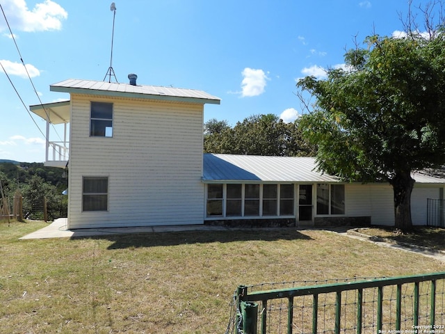 back of house featuring a lawn and a sunroom