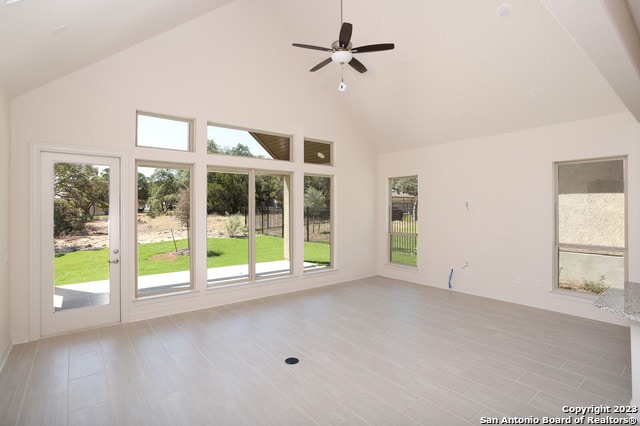 unfurnished room featuring ceiling fan, light wood-type flooring, and high vaulted ceiling