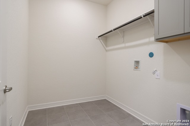 clothes washing area with cabinets, light tile flooring, and hookup for a washing machine