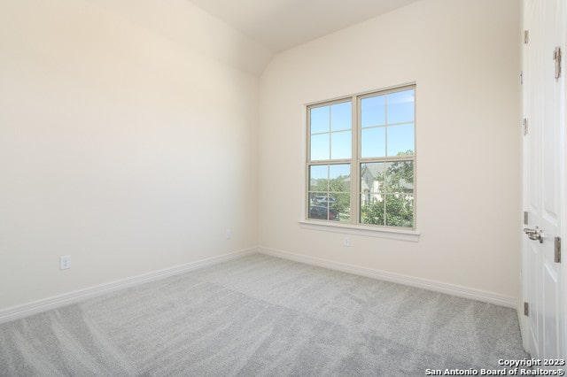 carpeted spare room featuring lofted ceiling