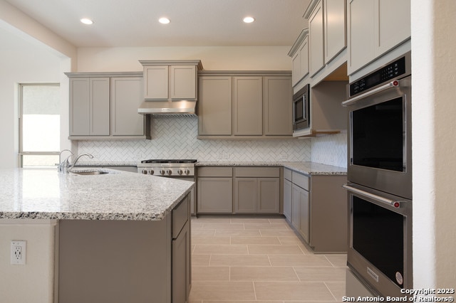 kitchen featuring appliances with stainless steel finishes, sink, gray cabinetry, and backsplash