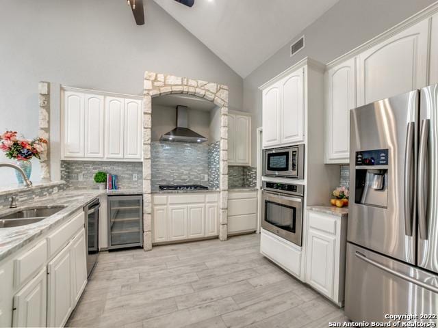 kitchen with stainless steel appliances, ceiling fan, tasteful backsplash, wall chimney exhaust hood, and sink