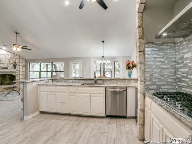 kitchen featuring white cabinets, lofted ceiling, ceiling fan with notable chandelier, and stainless steel appliances