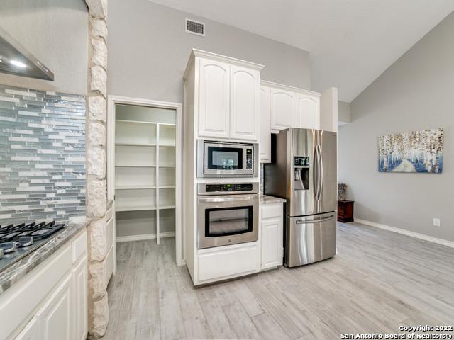 kitchen featuring white cabinets, light wood-type flooring, tasteful backsplash, and stainless steel appliances