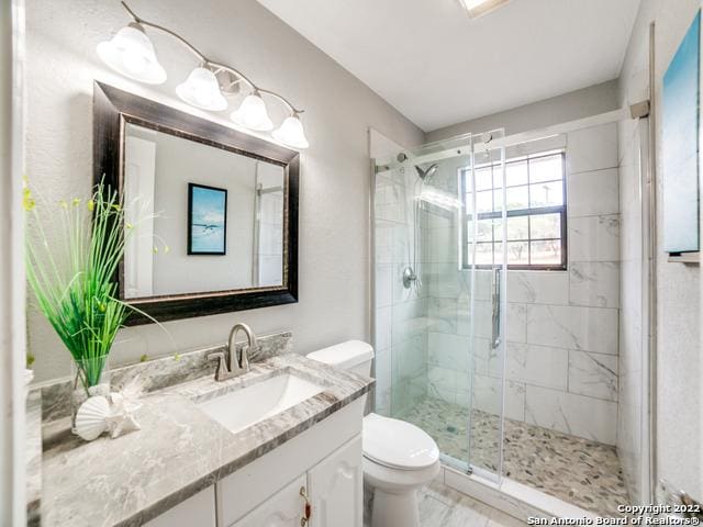 bathroom featuring toilet, a shower with door, tile floors, and large vanity