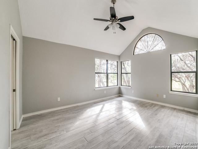 unfurnished room featuring high vaulted ceiling, ceiling fan, a wealth of natural light, and light wood-type flooring