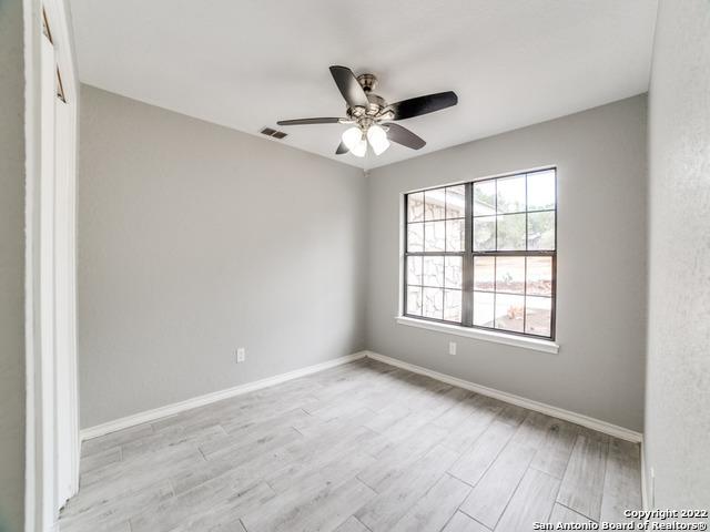 empty room with ceiling fan and light hardwood / wood-style flooring