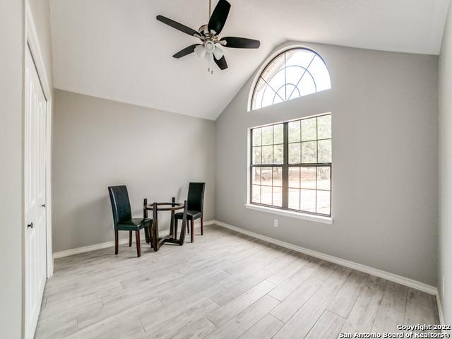 living area featuring ceiling fan, lofted ceiling, and light wood-type flooring