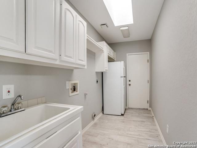 washroom with electric dryer hookup, hookup for a gas dryer, light hardwood / wood-style floors, sink, and cabinets