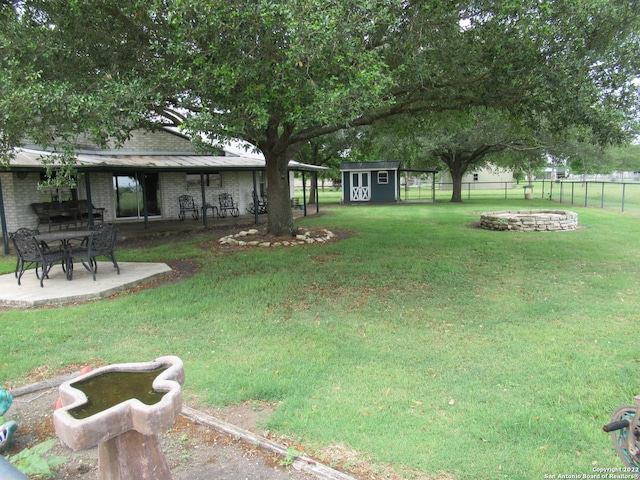 view of yard with an outdoor fire pit, a storage unit, and a patio