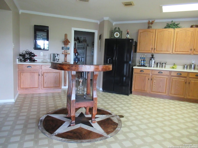 kitchen with light tile floors, ornamental molding, and black fridge