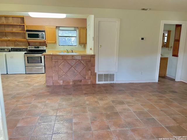 kitchen featuring sink, light tile floors, stainless steel appliances, and washer and clothes dryer