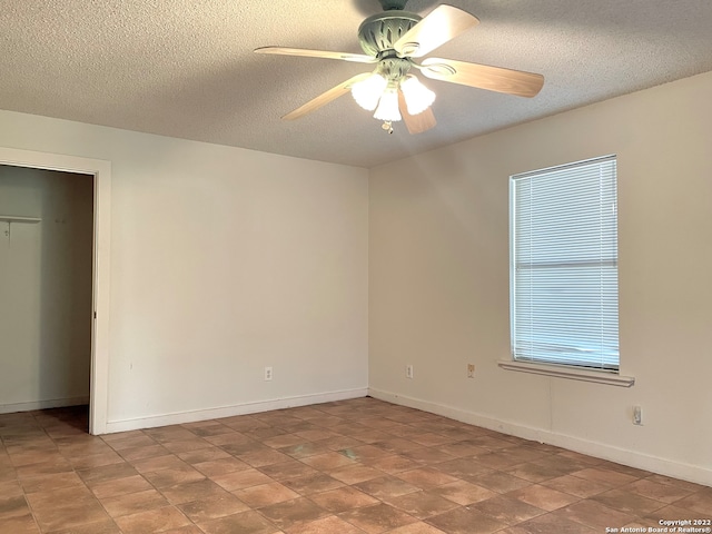 unfurnished bedroom featuring dark tile floors, ceiling fan, and a textured ceiling