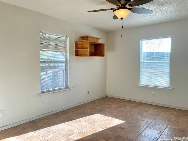 empty room featuring ceiling fan, a textured ceiling, and light tile floors