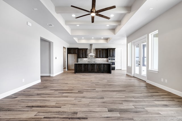 unfurnished living room featuring ceiling fan, light hardwood / wood-style flooring, and beamed ceiling