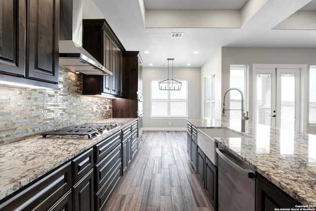 kitchen with sink, wall chimney exhaust hood, dark hardwood / wood-style floors, pendant lighting, and appliances with stainless steel finishes