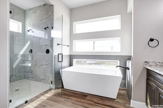 bathroom featuring vanity, a healthy amount of sunlight, wood-type flooring, and independent shower and bath