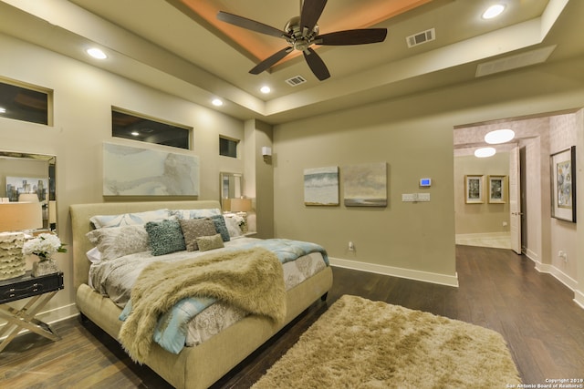 bedroom with a raised ceiling, dark hardwood / wood-style floors, and ceiling fan