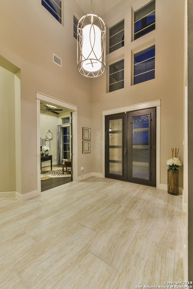 unfurnished living room featuring a high ceiling, ceiling fan, and light tile floors