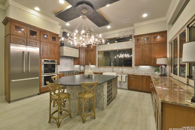 kitchen featuring backsplash, a kitchen island, an inviting chandelier, and appliances with stainless steel finishes