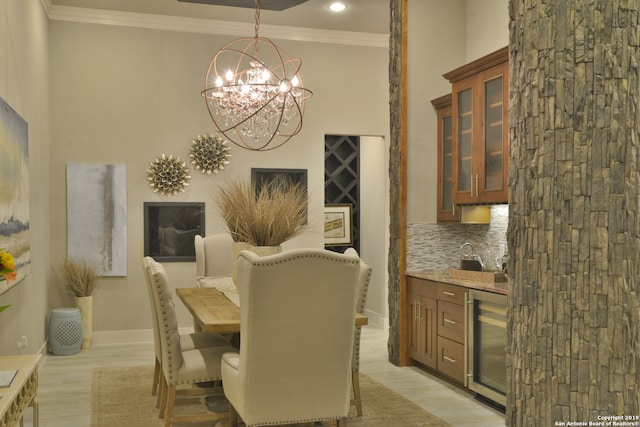 dining space featuring a chandelier, wine cooler, and crown molding